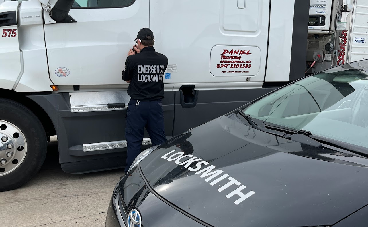 Locksmith working at a truck cab door beside a branded service car