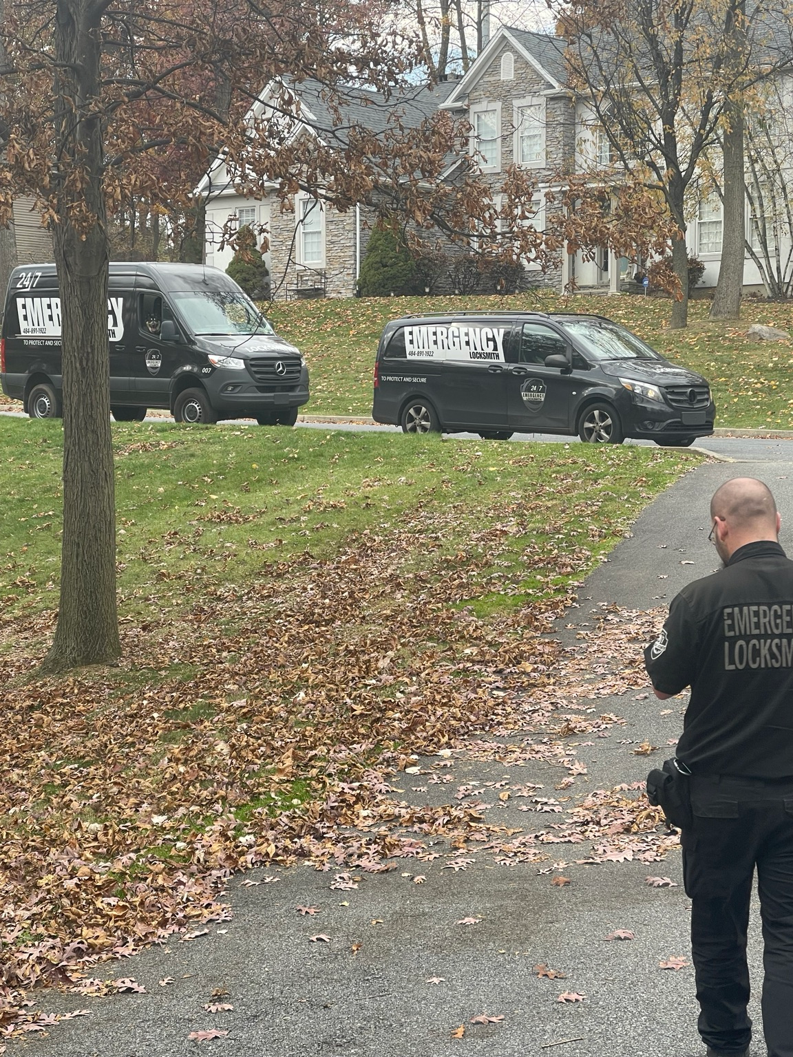 Two branded Emergency Locksmith vans with a technician in the foreground